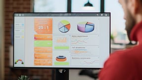 Fotografía de un usuario revisando un panel con métricas de rendimiento y gráficos organizacionales para CMMI