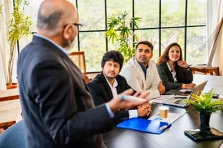 Fotografía de un consultor sénior exponiendo estrategias de optimización a un equipo directivo a través de un CMMI Licensed Partner