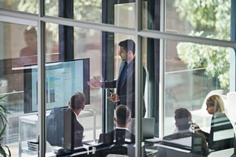 Fotografía de un consultor presentado métricas e informes de para la certificación ISO 27001 ante un equipo corporativo