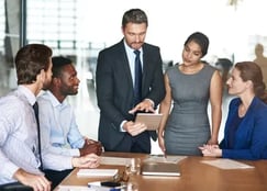 Fotografía de un consultor mostrando avances en una tableta digital durante una evaluación CMMI con su equipo