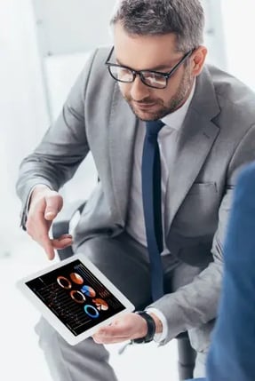 Fotografía de hombre de negocios con lentes y traje gris concentrado revisando documentos sobre madurez de procesos